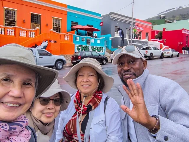 Un groupe de touristes prenant un selfie devant des maisons colorées.