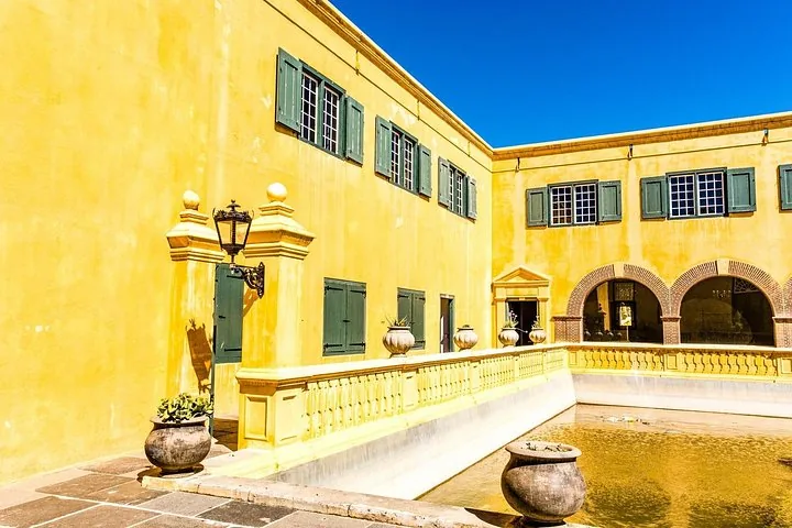 Ein Innenhof eines gelben historischen Gebäudes mit einem flachen Becken.